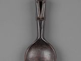 an old spoon with a man on it sitting on top of a table