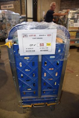 un chariot bleu sur lequel est accrochée une pancarte, dans un entrepôt