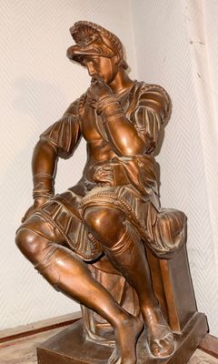 a bronze statue of a man sitting on a chair