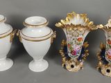 trois vases blancs ornés de bordures dorées et décorés de fleurs, disposés les uns à côté des autres