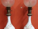 une paire de lampes en verre blanc et rose posées sur un support rouge