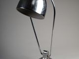 une photo d'une lampe de bureau argentée posée sur une surface blanche