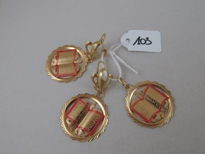 three gold plated charms with books on them on a white surface