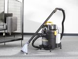 un aspirateur posé par terre à côté d'un lit