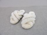 une paire de chaussons blancs ornés d'un nœud, posés sur un fond gris