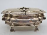 an antique silver plate with a lid on a white surface