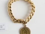 Gros plan sur un bracelet en or orné d'une pièce de monnaie