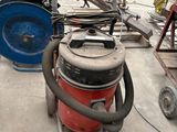 un aspirateur rouge et bleu posé par terre à côté d'un chariot bleu