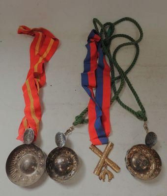 three medals and a ribbon hang on a white surface