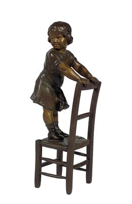 statue en bronze représentant une petite fille assise sur une chaise, les mains posées sur le dossier de celle-ci