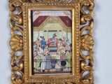 an ornate gold frame with a painting of a group of people on a stage
