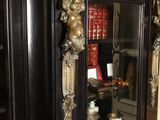 a black cabinet with gold trim and a mirror on it