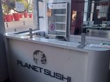 un comptoir blanc sur lequel est accrochée une enseigne indiquant « Planet Sushi »