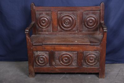un vieux banc en bois dont le dossier est orné de sculptures