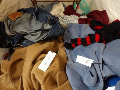 a pile of clothes on a bed with a tag on it