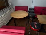 tables and stools in a small room with a window and a radiator
