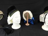 Plusieurs chapeaux sont alignés sur une tête de mannequin, sur fond noir.