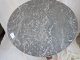 a round table with a marble top sitting on a white cloth