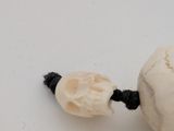 a small white skull on a string with a black cord