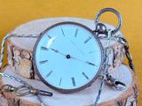 une montre de poche en argent posée sur un morceau de bois