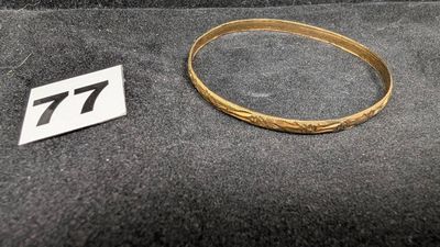 un gros plan d'un bracelet en or sur lequel figure le chiffre 77