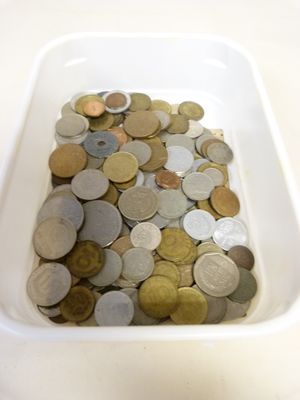 un bol blanc rempli d'une multitude de pièces de monnaie posé sur une table