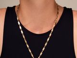 une femme vêtue d'un débardeur noir et portant un collier en or
