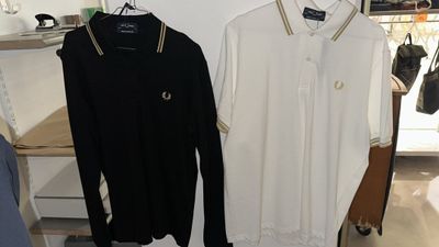 two men ' s shirts hanging on a rack in a clothing store