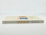 two books are stacked on top of each other on a white surface