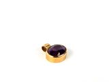 un gros plan d'un pendentif plaqué or orné d'une pierre violette