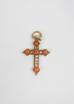 une croix en or ornée de perles de corail sur fond blanc