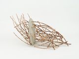 une sculpture représentant un oiseau, réalisée à partir de brindilles, posée sur une surface blanche