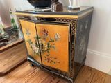 a small cabinet with a vase on top of it