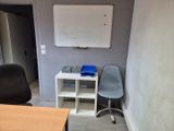 un bureau avec une chaise et un tableau blanc accroché au mur