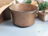 a large copper pot sitting on the floor next to boxes