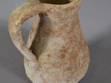 a small brown vase with a handle on a table