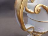 a white and gold vase with a gold decoration on it