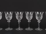 six empty wine glasses lined up against a black background