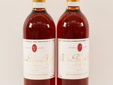 two bottles of wine sitting next to each other on a white surface