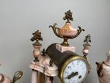 a clock sitting on top of a table next to vases
