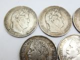 six silver coins of different sizes and shapes on a white surface