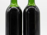 two bottles of wine sitting next to each other on a white surface