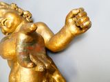 une statue en or représentant un bébé tenant un oiseau