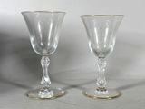 pair of clear glass goblets with gold rims on a table