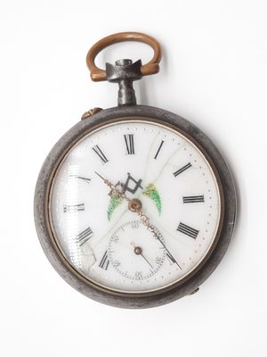 une vieille montre de poche accrochée à un mur blanc