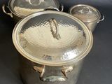 three metal pots with lids sitting on a black surface
