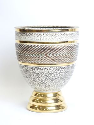 a close up of a silver and gold vase on a white background