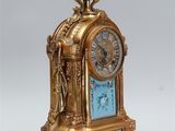 a gold and blue clock with a blue vase on top of it