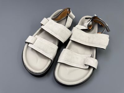 white leather sandals with straps on a gray surface