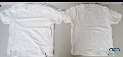 two white t - shirts sitting on top of a table next to each other